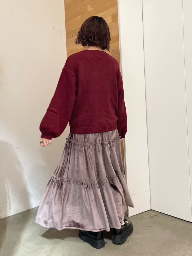 パープル系のスカート、ブラック系のローファー、レッド系のニット/セーターを着用したレディースの秋コーディネートの3枚目の写真