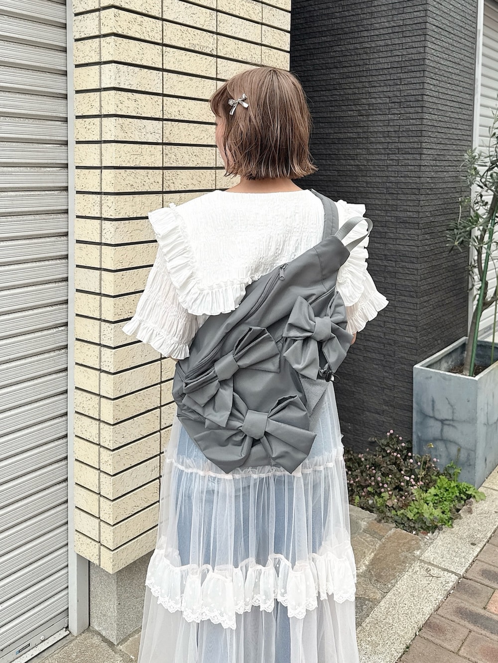 グレー系のショルダーバッグ、ホワイト系のシャツ/ブラウス、ピンク系のスカートを着用したレディースの春コーディネートの6枚目の写真