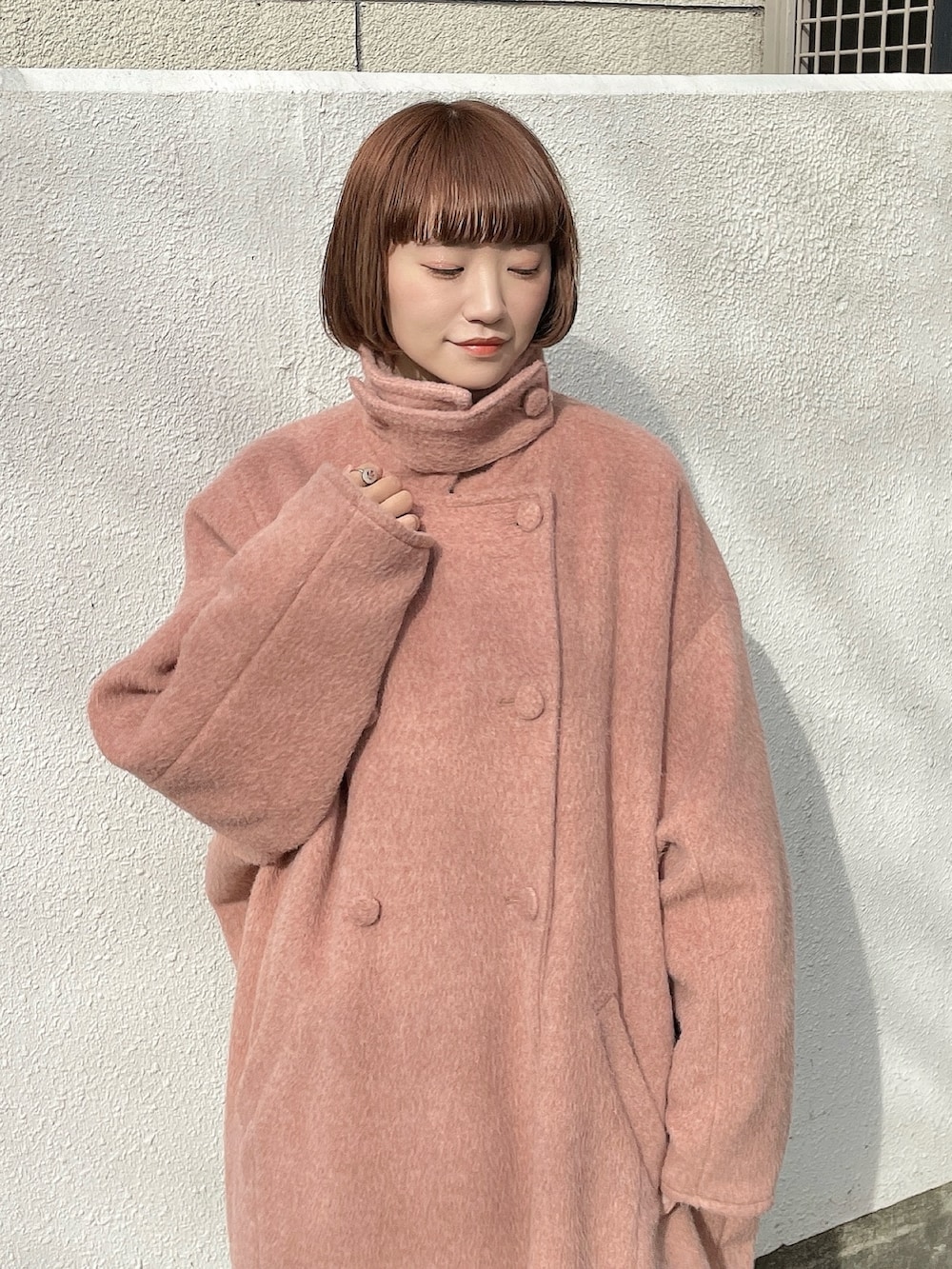 ピンク系のチェスターコート、ブラック系のスカート、グレー系のシャツ/ブラウスを着用したレディースの冬コーディネートの5枚目の写真