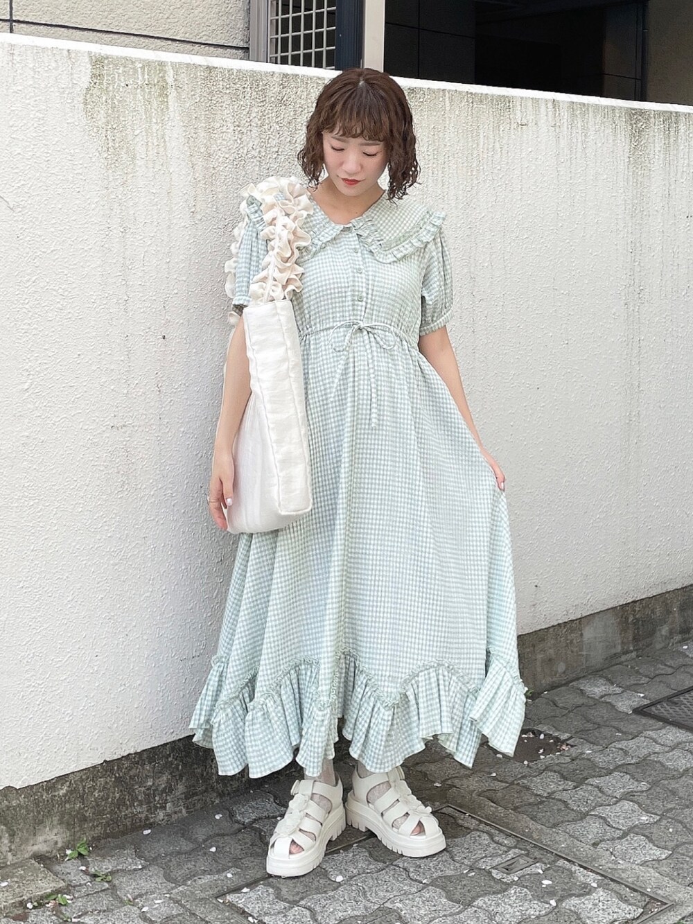 グリーン系のワンピース、ホワイト系のトートバッグ、ホワイト系のサンダルを着用したレディースの春コーディネートの2枚目の写真