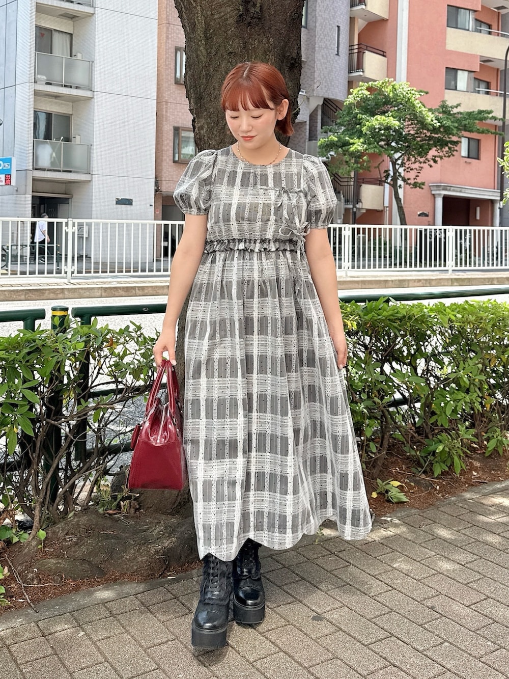 ブラック系のワンピース、レッド系のハンドバッグ、ブラック系のブーツを着用したレディースの夏コーディネートの2枚目の写真
