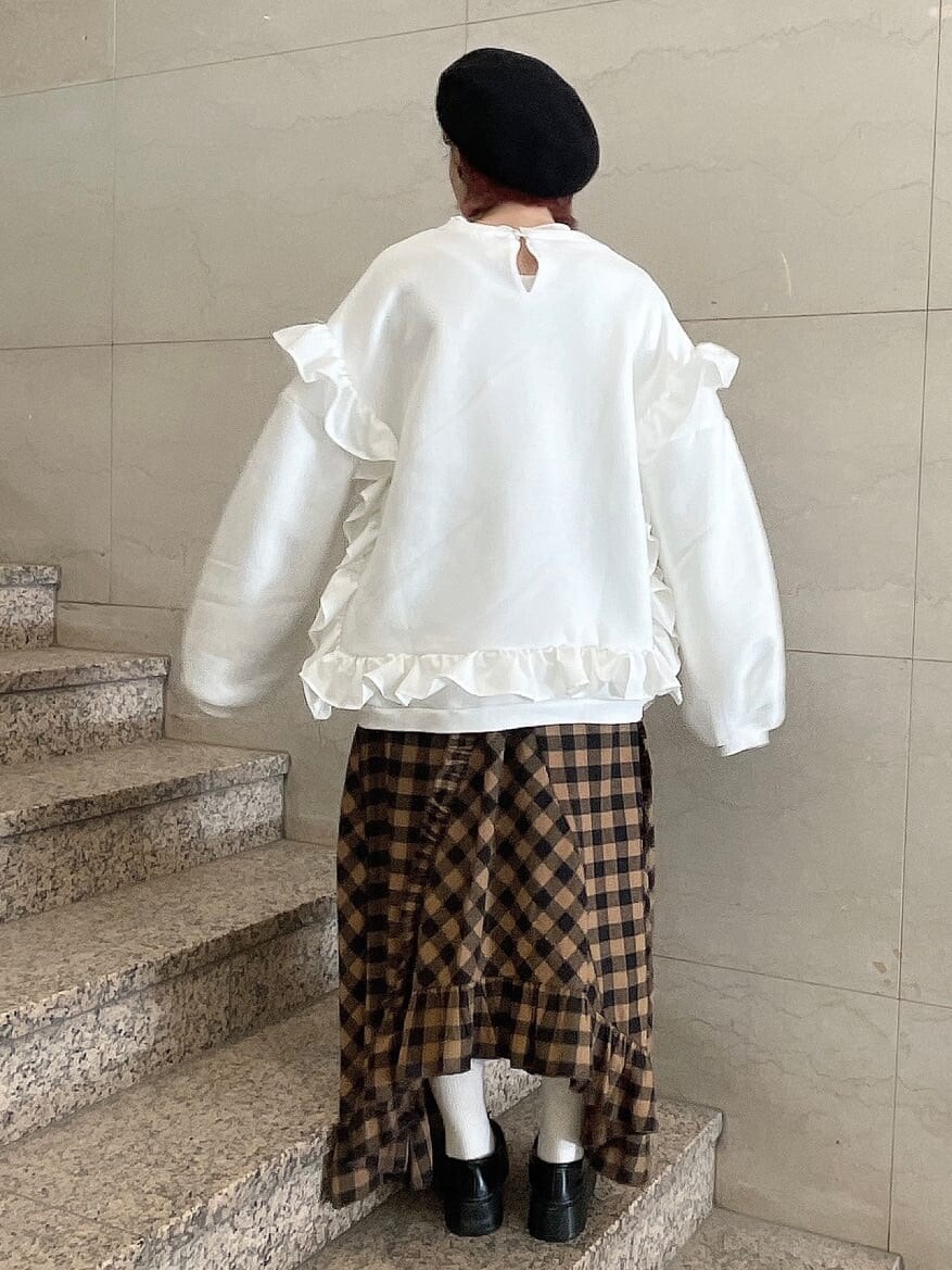 オレンジ系のスカート、ブラック系のローファー、ホワイト系のTシャツ/カットソーを着用したレディースの冬コーディネートの3枚目の写真