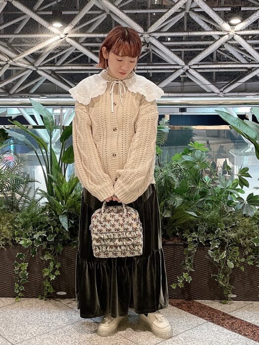 ベージュ系のスカート、ホワイト系のローファー、グリーン系のショルダーバッグを着用したレディースの冬コーディネートの2枚目の写真