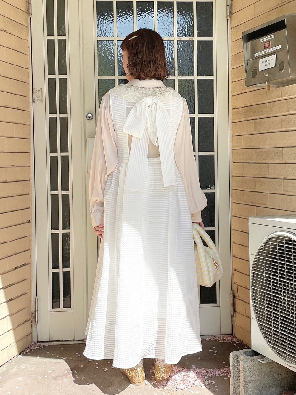 ゴールド系のパンプス、ホワイト系のチュニック、ホワイト系のワンピースを着用したレディースの春コーディネートの3枚目の写真