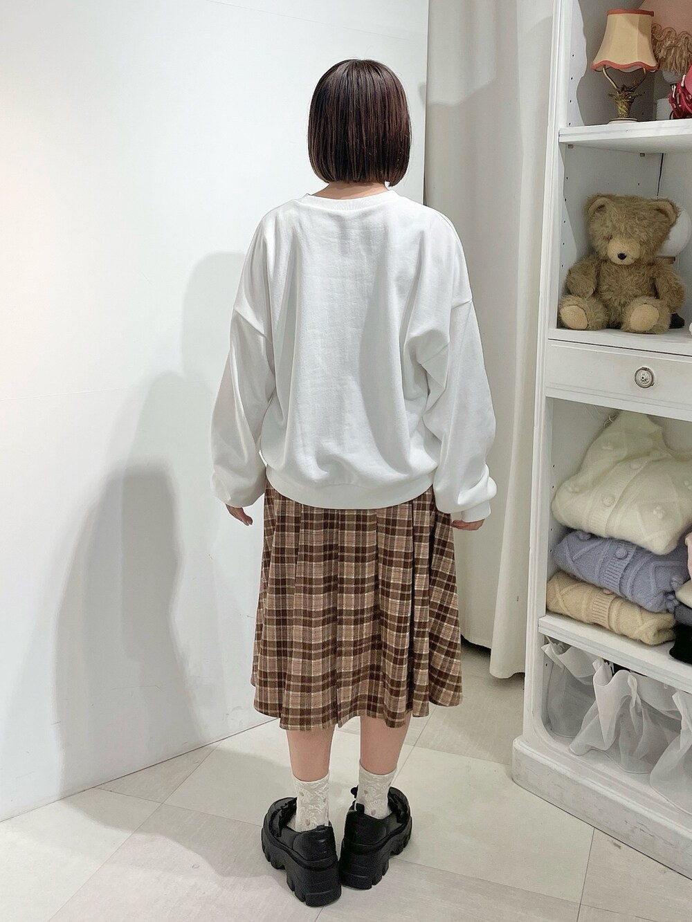 ブラウン系のスカート、ホワイト系のスウェット、ブラウン系のブルゾンを着用したレディースの秋コーディネートの7枚目の写真