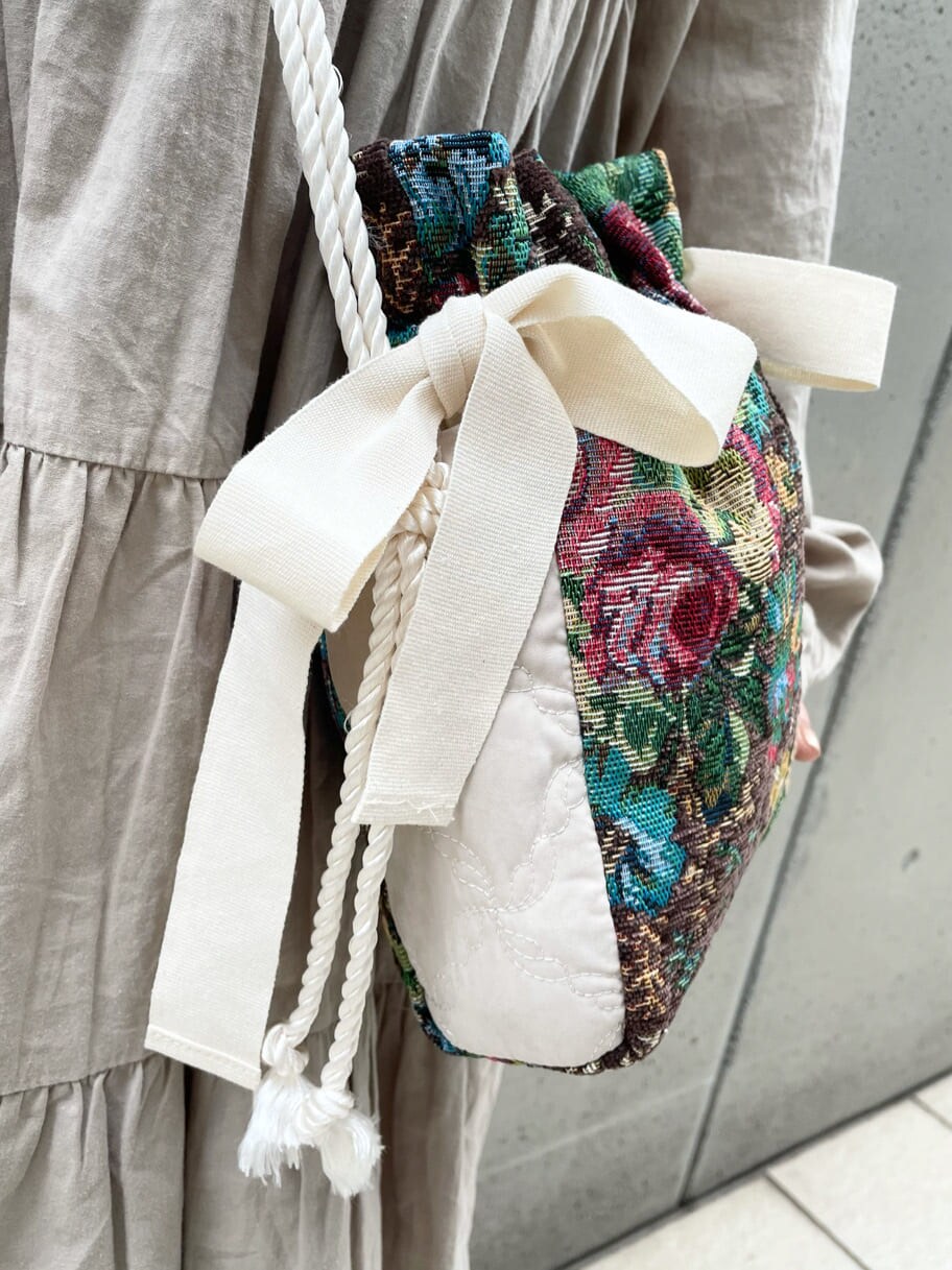 ブラウン系のハンドバッグ、ベージュ系のワンピース、グレー系のサンダルを着用したレディースの夏コーディネートの7枚目の写真