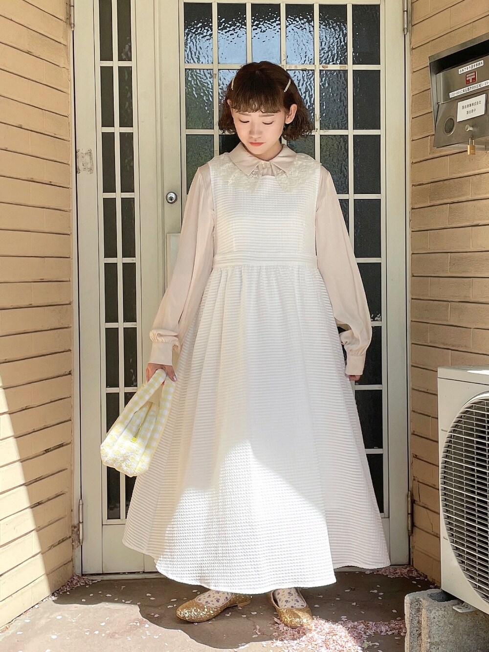 ゴールド系のパンプス、ホワイト系のチュニック、ホワイト系のワンピースを着用したレディースの春コーディネートの2枚目の写真