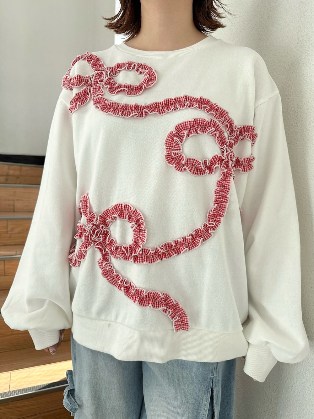 ホワイト系のブルゾン、ホワイト系のスウェット、ブルー系のデニムパンツを着用したレディースの冬コーディネートの8枚目の写真