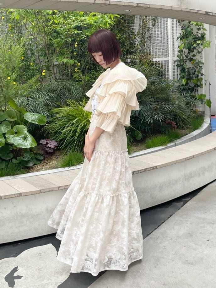 ベージュ系のスカート、ホワイト系のTシャツ/カットソー、ベージュ系のパンプスを着用したレディースの春コーディネートの2枚目の写真