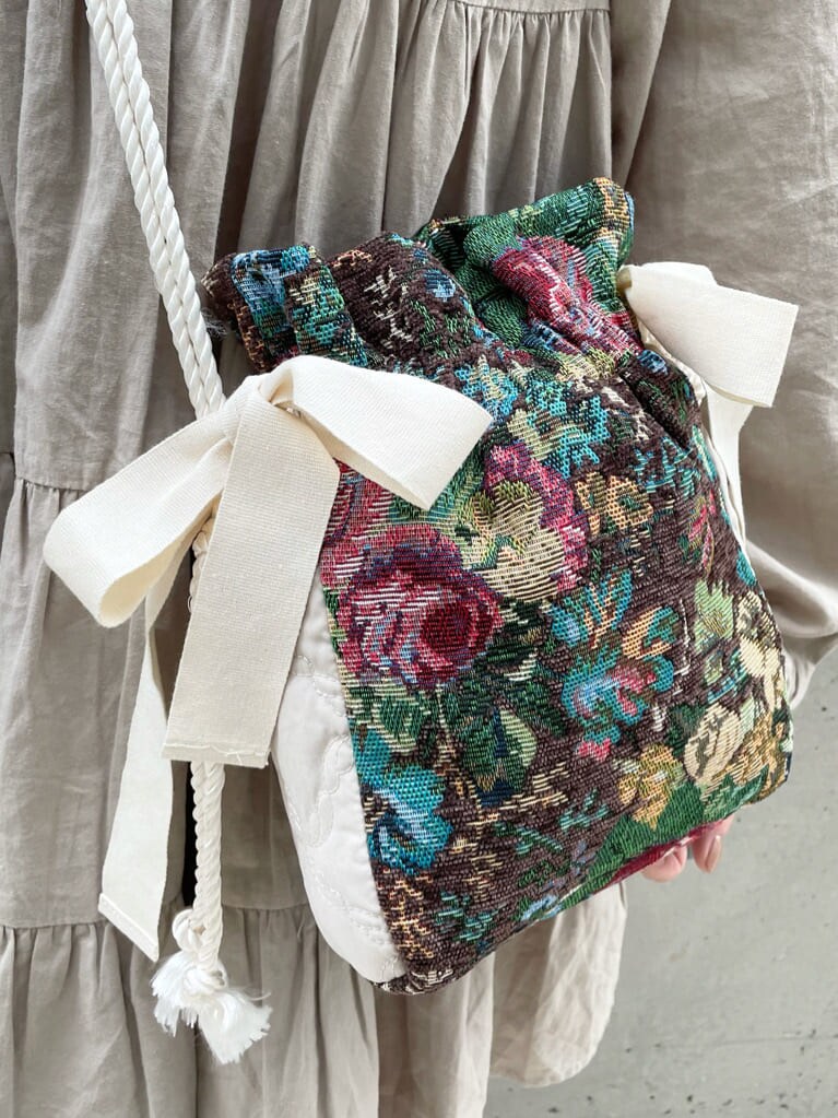 ブラウン系のハンドバッグ、ベージュ系のワンピース、グレー系のサンダルを着用したレディースの夏コーディネートの6枚目の写真