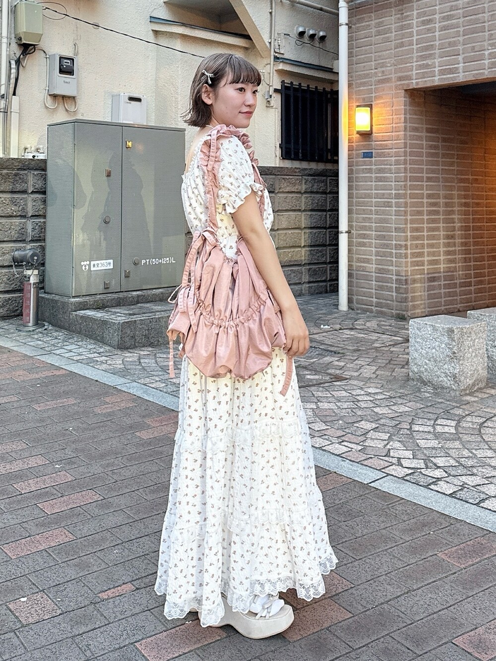 ピンク系のトートバッグ、ベージュ系のサンダル、ホワイト系のワンピースを着用したレディースの春コーディネートの3枚目の写真