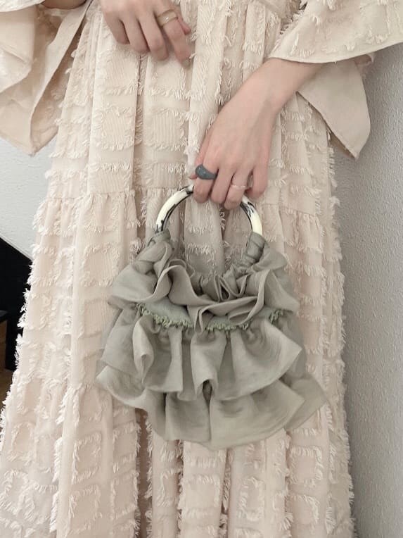 ベージュ系のドレス、グリーン系のハンドバッグ、ベージュ系のブーツを着用したレディースの夏コーディネートの6枚目の写真