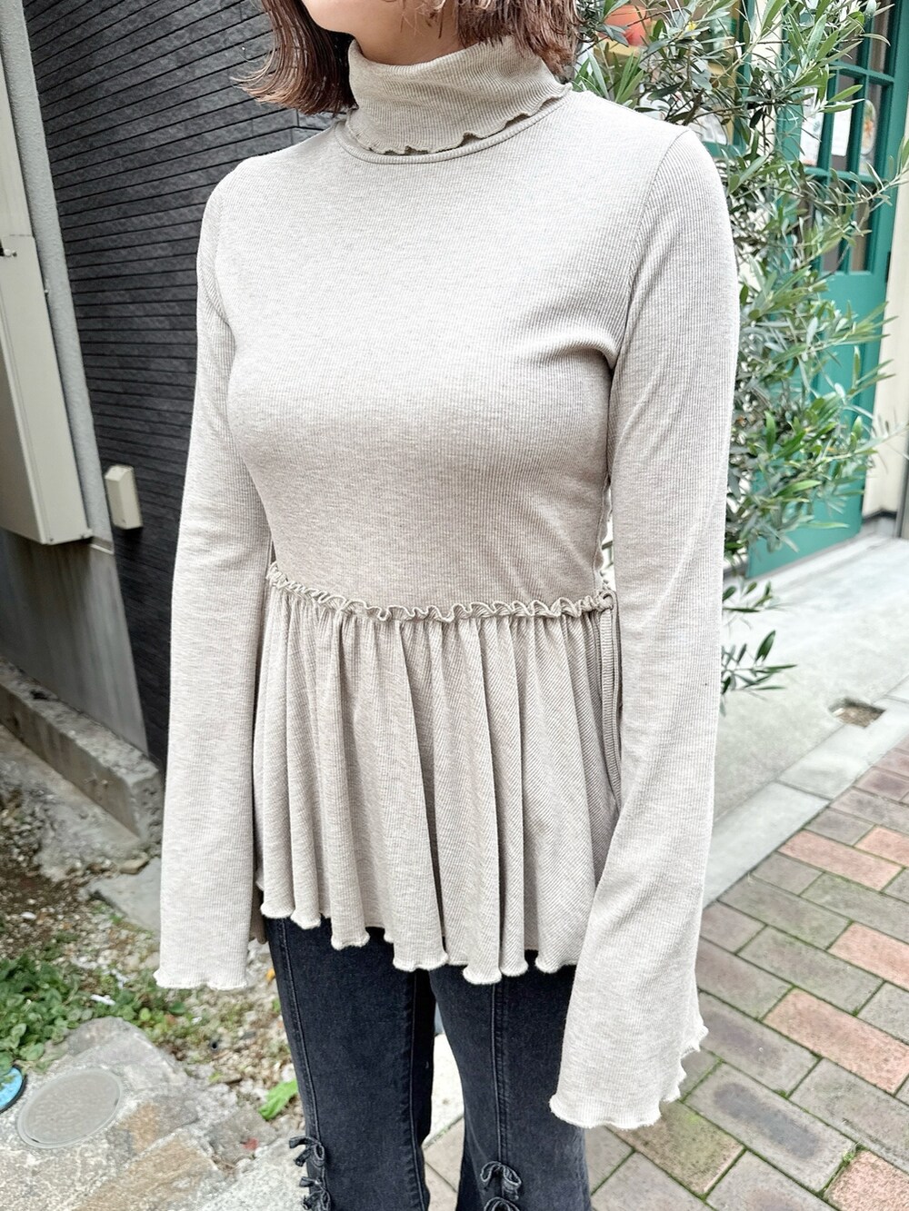 ブラウン系のニット/セーター、ブラック系のハンドバッグ、ブラック系のデニムパンツを着用したレディースの夏コーディネートの5枚目の写真