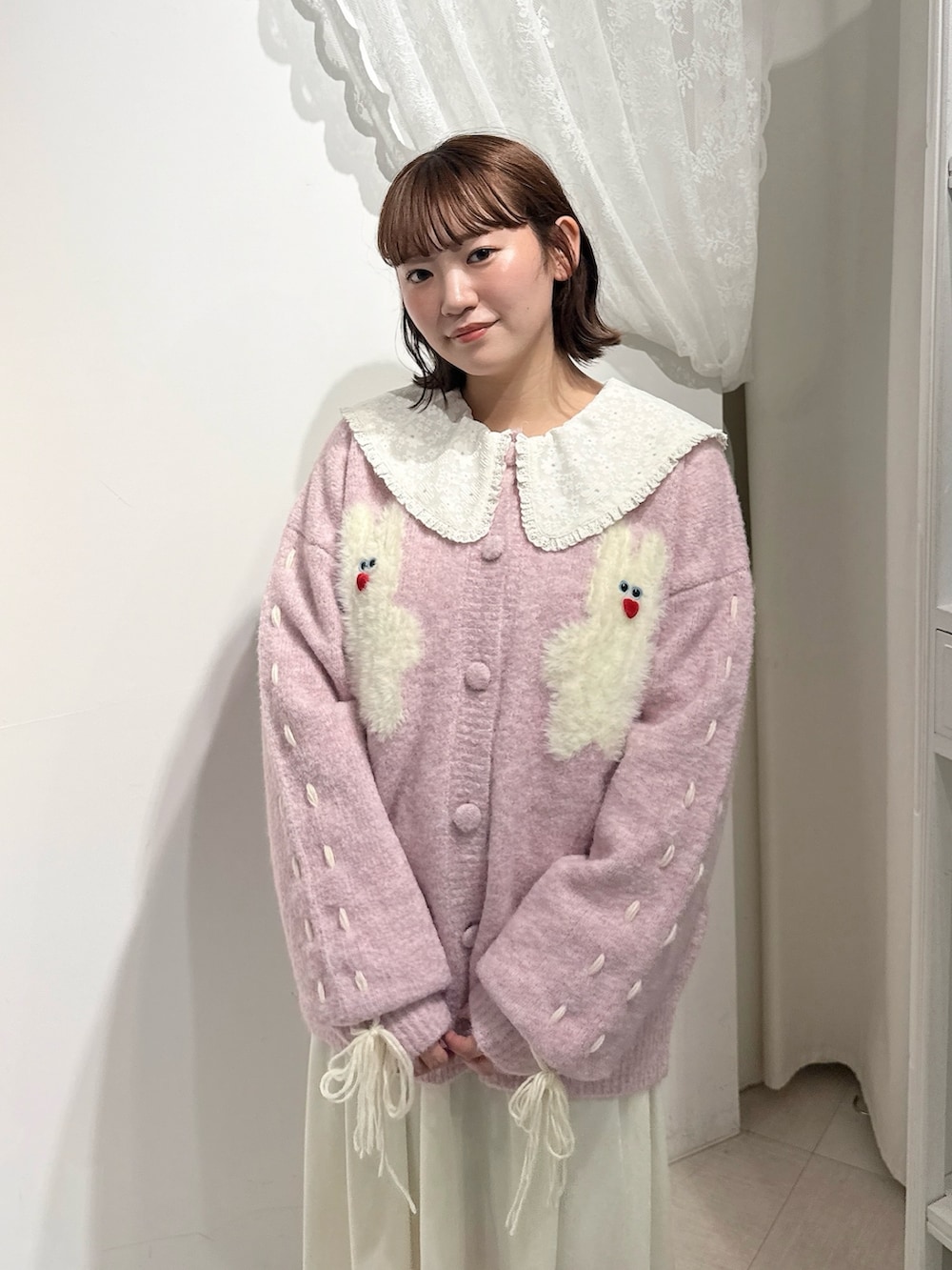 ピンク系のブーツ、ピンク系のカーディガン/ボレロ、ホワイト系のワンピースを着用したレディースの秋コーディネートの4枚目の写真