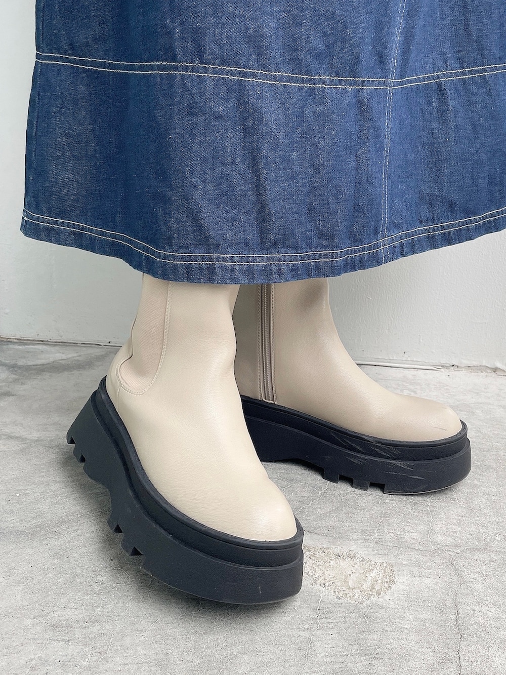 ホワイト系のトートバッグ、ベージュ系のブーツ、ブルー系のワンピースを着用したレディースの秋コーディネートの5枚目の写真