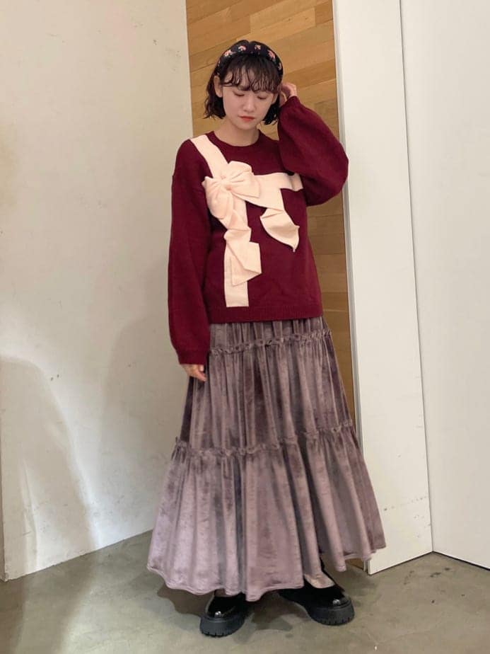 パープル系のスカート、ブラック系のローファー、レッド系のニット/セーターを着用したレディースの秋コーディネートの2枚目の写真