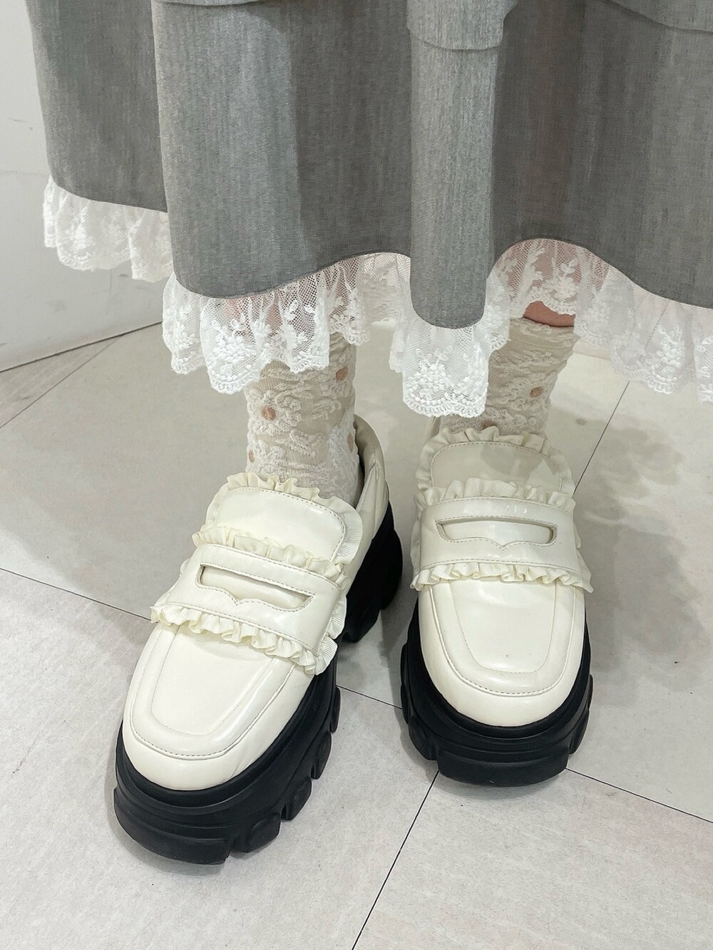 グレー系のスカート、ピンク系のニット/セーター、ホワイト系のローファーを着用したレディースの秋コーディネートの8枚目の写真