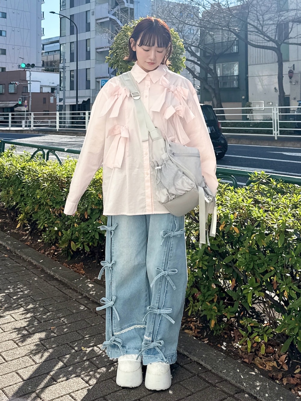 ピンク系のシャツ/ブラウス、グレー系のメッセンジャーバッグ、ブルー系のデニムパンツを着用したレディースの冬コーディネートの2枚目の写真