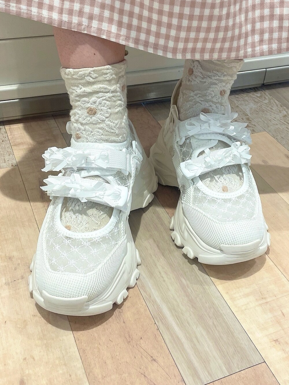 ピンク系のワンピース、ホワイト系のカーディガン/ボレロ、ホワイト系のスニーカーを着用したレディースの冬コーディネートの7枚目の写真