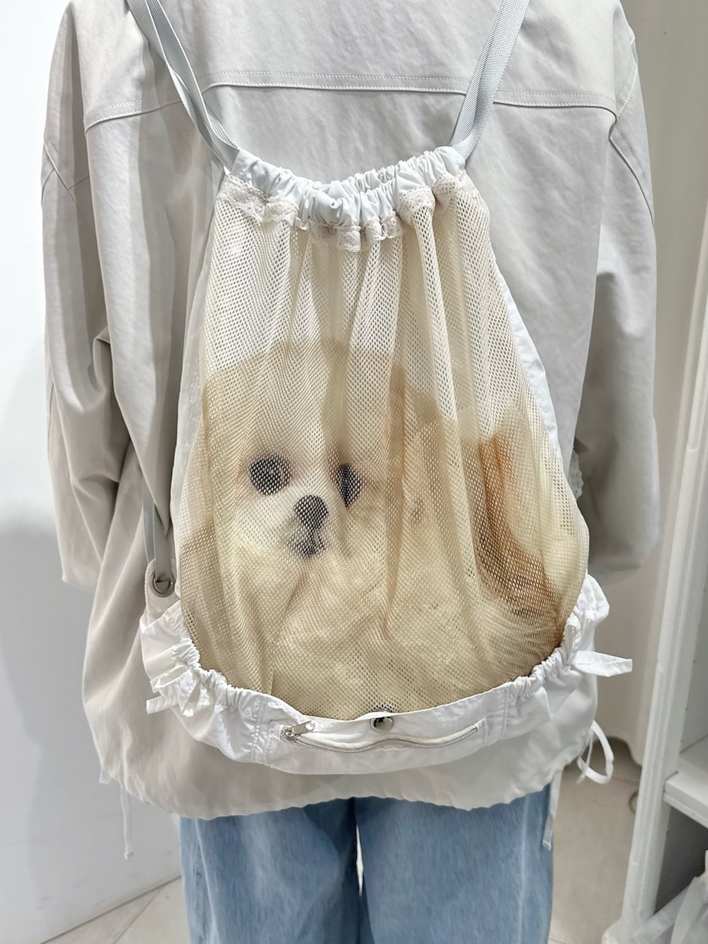 ホワイト系のブルゾン、ホワイト系のバックパック/リュック、ブルー系のデニムパンツを着用したレディースの冬コーディネートの7枚目の写真