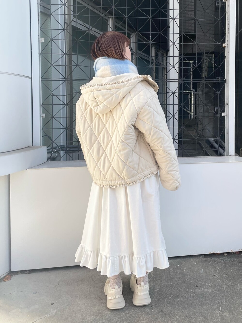 ホワイト系のダウンジャケット/コート、ホワイト系のワンピース、ホワイト系のスニーカーを着用したレディースの冬コーディネートの3枚目の写真