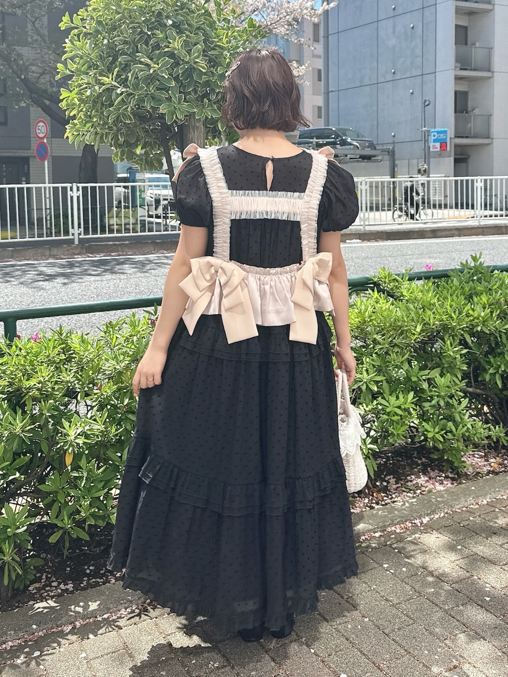ブラック系のワンピース、ピンク系のハンドバッグ、ブラック系のバレエシューズを着用したレディースの春コーディネートの3枚目の写真