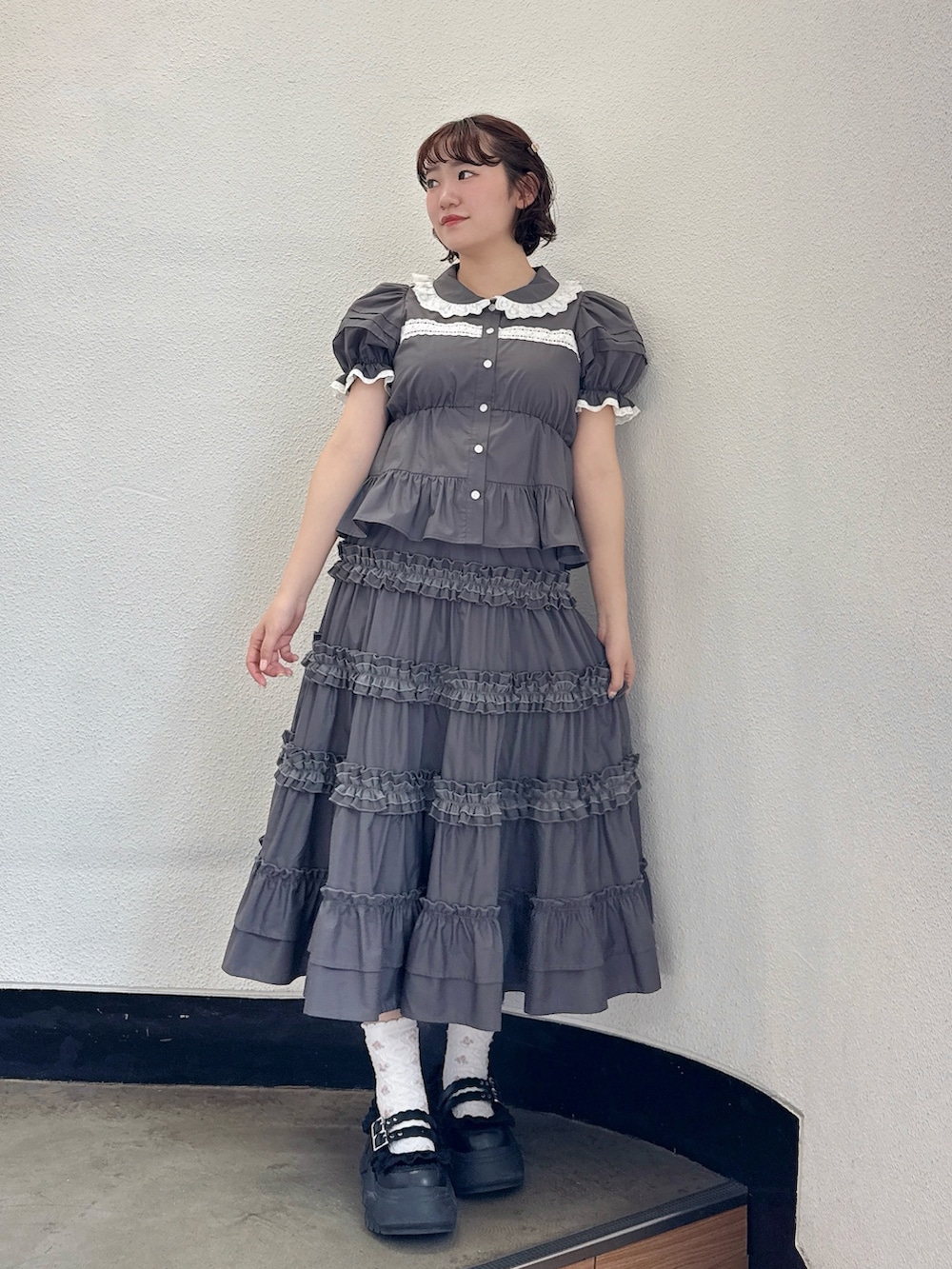 グレー系のシャツ/ブラウス、グレー系のスカート、ブラック系のスニーカーを着用したレディースの春コーディネートの2枚目の写真