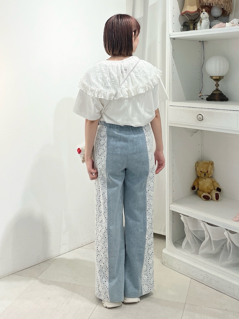 ブルー系のデニムパンツ、ホワイト系のスニーカー、ホワイト系のショルダーバッグを着用したレディースの春コーディネートの3枚目の写真