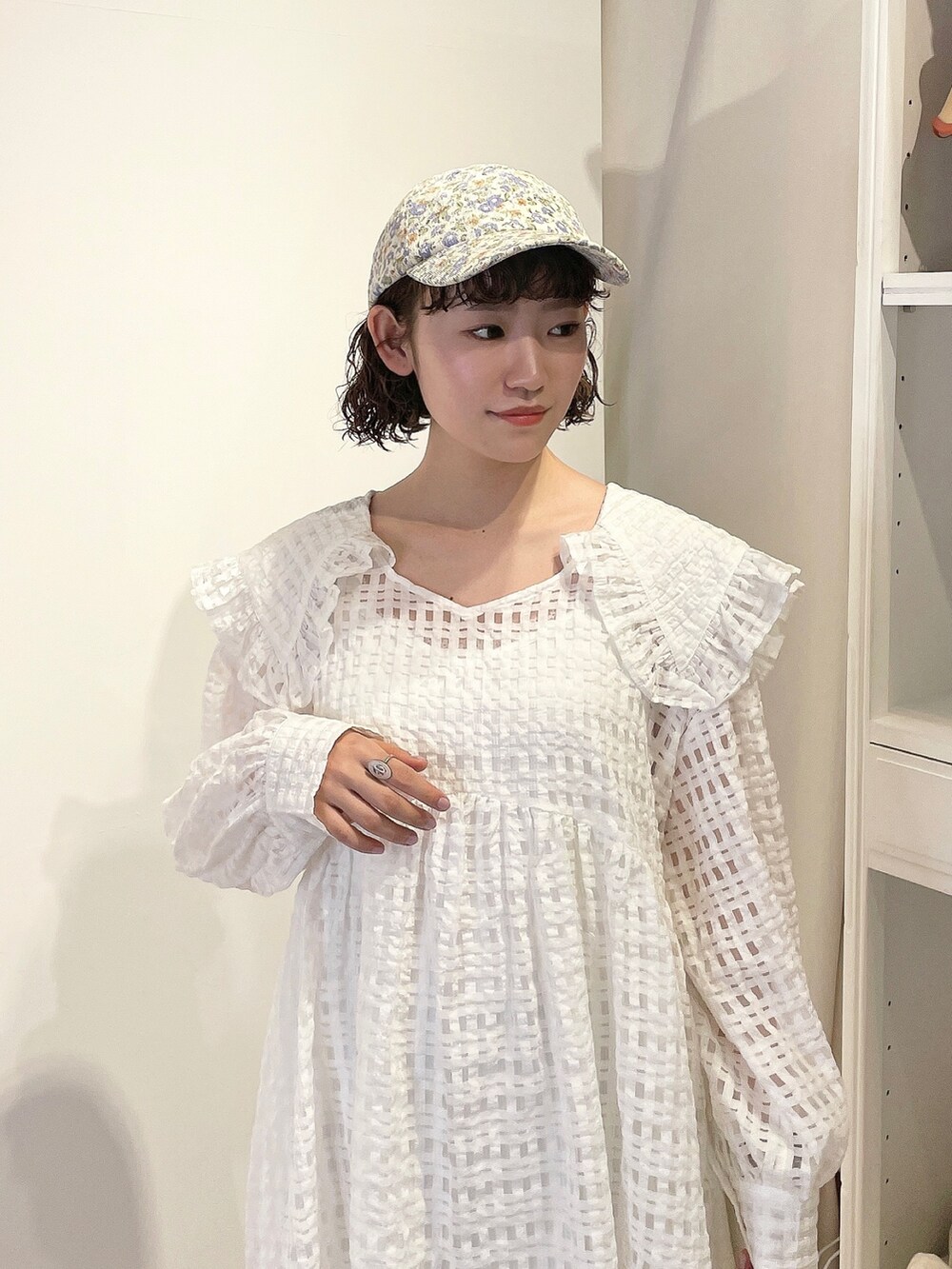 ホワイト系のワンピース、ホワイト系のサンダル、パープル系のキャップを着用したレディースの春コーディネートの4枚目の写真