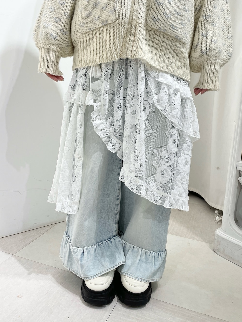 ホワイト系のニット/セーター、ブルー系のデニムパンツ、ホワイト系のスカートを着用したレディースの秋コーディネートの6枚目の写真