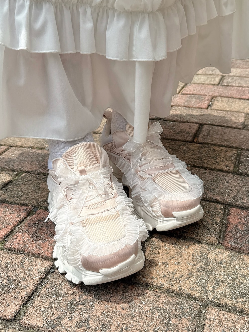 ホワイト系のワンピース、ピンク系のスニーカー、ピンク系の長傘を着用したレディースの春コーディネートの7枚目の写真