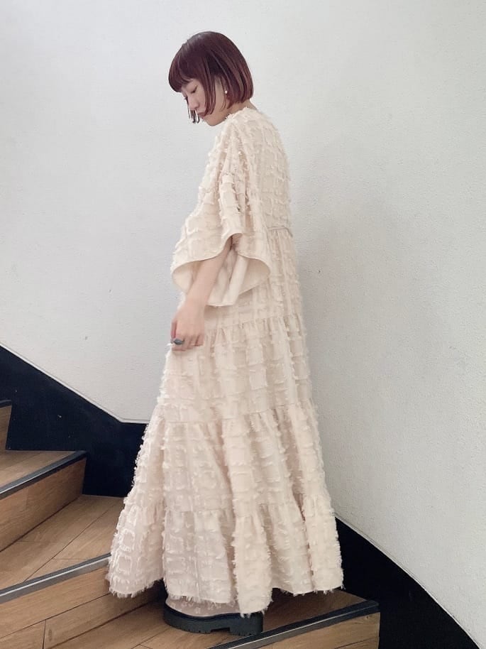 ベージュ系のドレス、グリーン系のハンドバッグ、ベージュ系のブーツを着用したレディースの夏コーディネートの3枚目の写真