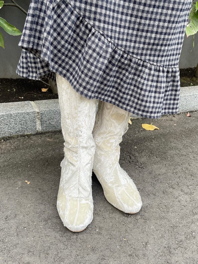 ホワイト系のブーツ、ブラック系のスカート、ホワイト系のショルダーバッグを着用したレディースの冬コーディネートの4枚目の写真