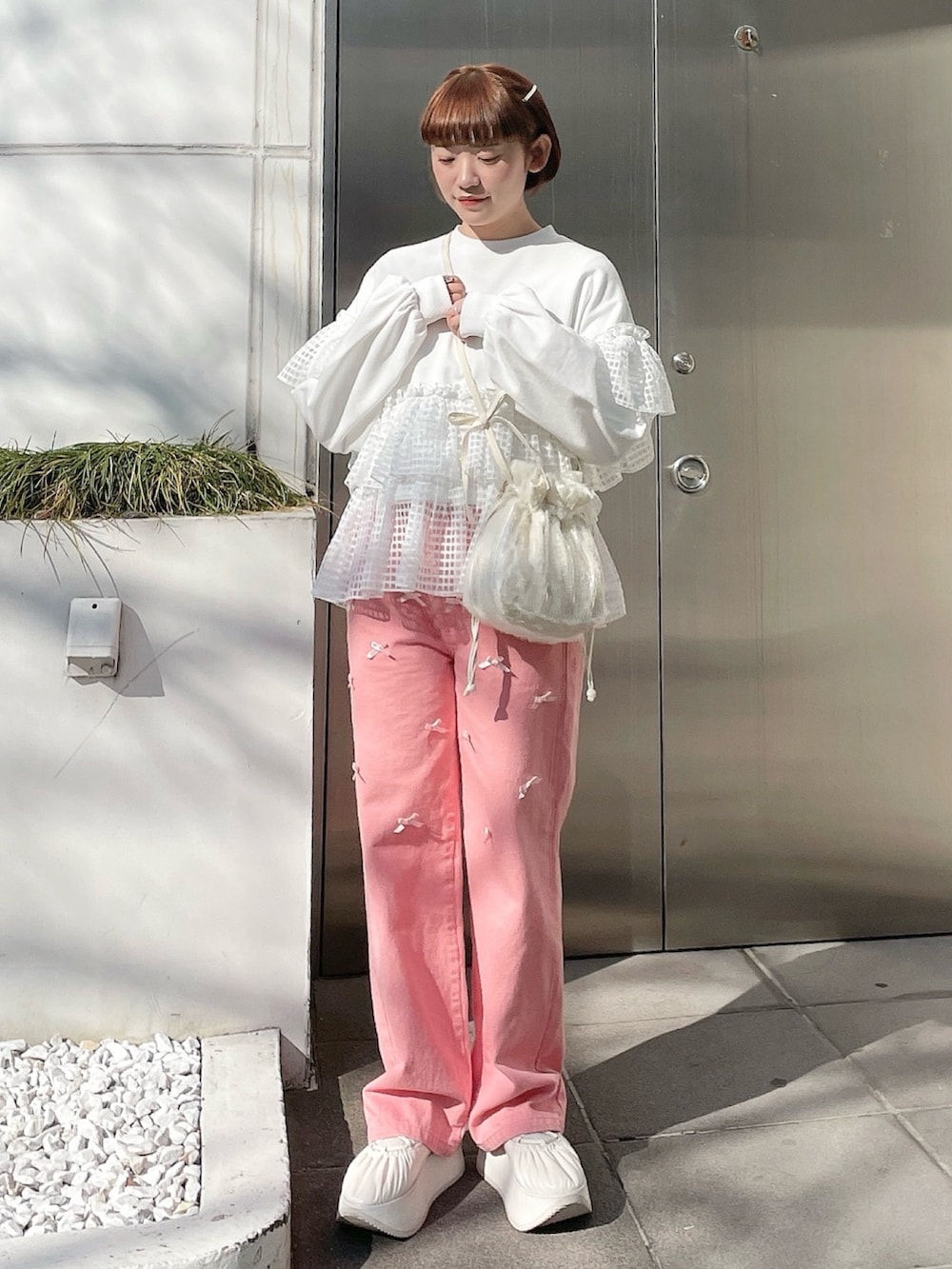 ホワイト系のスウェット、ピンク系のデニムパンツ、ホワイト系のショルダーバッグを着用したレディースの冬コーディネートの2枚目の写真