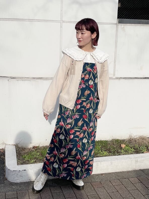 ホワイト系のブーツ、ブルー系のジャンパースカート、ホワイト系のカーディガン/ボレロを着用したレディースの冬コーディネートの2枚目の写真