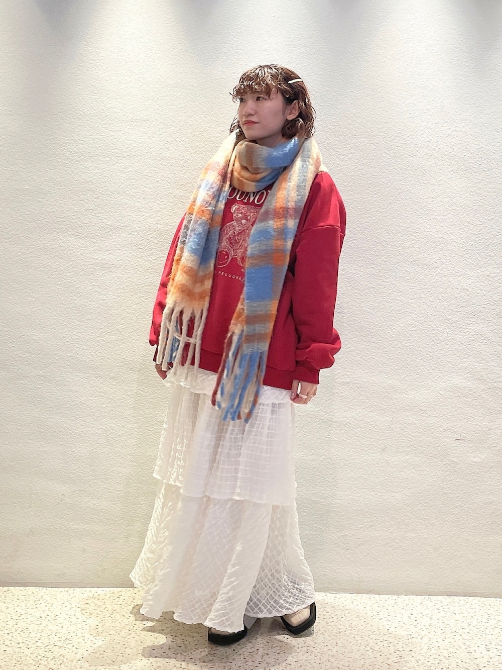 ホワイト系のスカート、ホワイト系のモカシン/デッキシューズ、レッド系のTシャツ/カットソーを着用したレディースの冬コーディネートの2枚目の写真