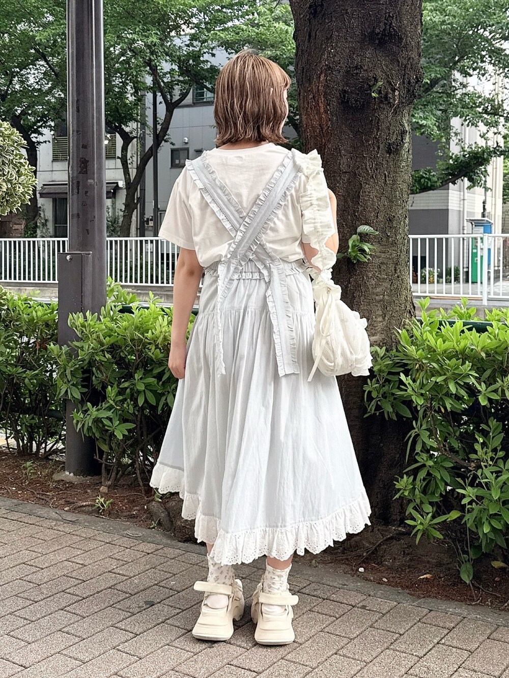ホワイト系のTシャツ/カットソー、グリーン系のジャンパースカート、ホワイト系のショルダーバッグを着用したレディースの春コーディネートの5枚目の写真