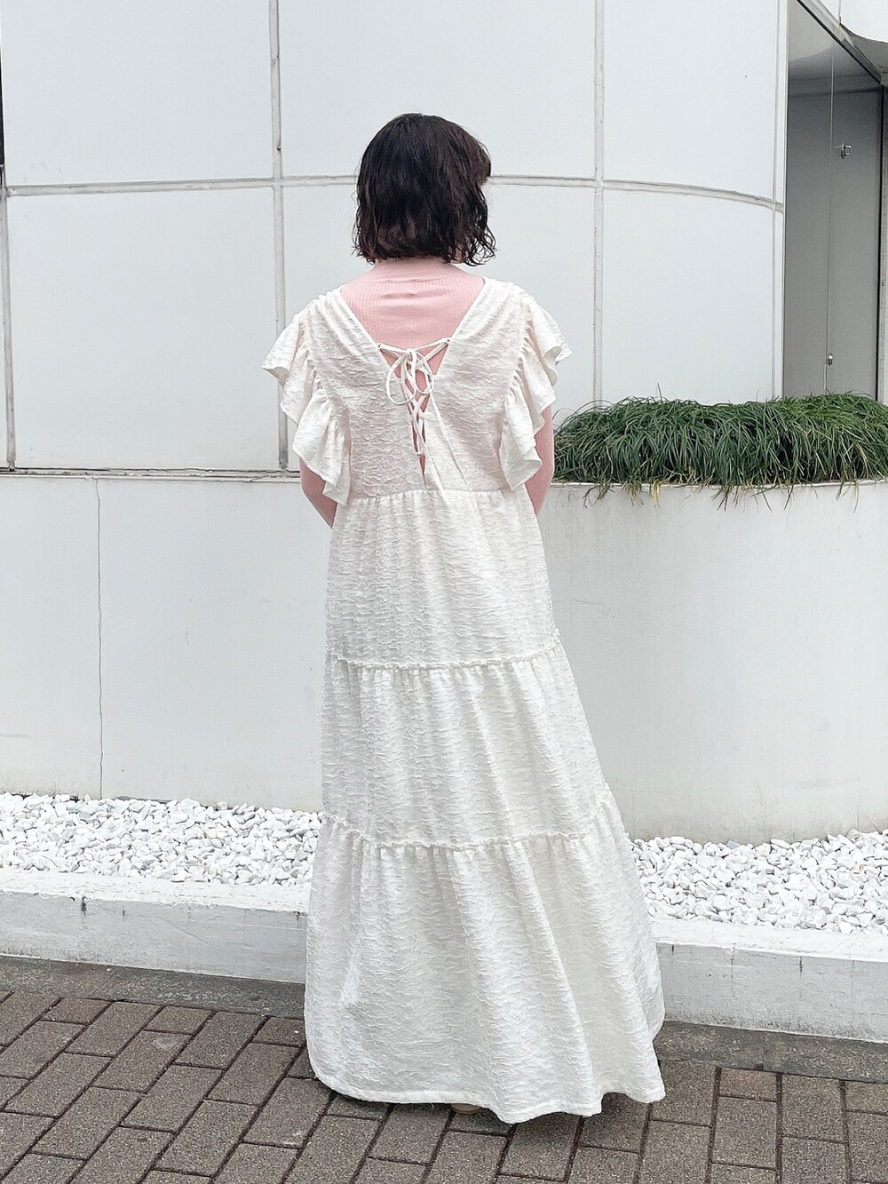 ピンク系のニット/セーター、ホワイト系のワンピース、ベージュ系のブーツを着用したレディースの冬コーディネートの3枚目の写真