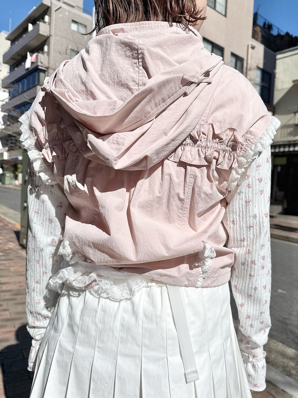 ピンク系のベスト、ピンク系のTシャツ/カットソー、ホワイト系のスカートを着用したレディースの春コーディネートの6枚目の写真