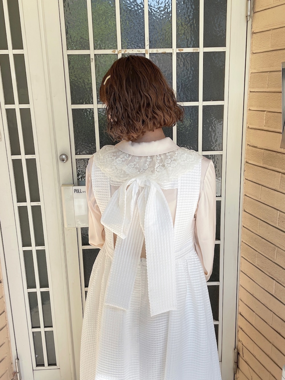 ゴールド系のパンプス、ホワイト系のチュニック、ホワイト系のワンピースを着用したレディースの春コーディネートの5枚目の写真