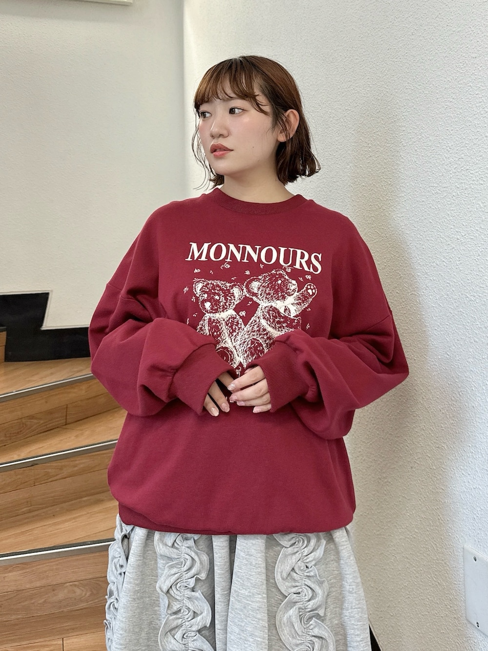 レッド系のスウェット、グレー系のスカート、ブラウン系のハンドバッグを着用したレディースの夏コーディネートの4枚目の写真