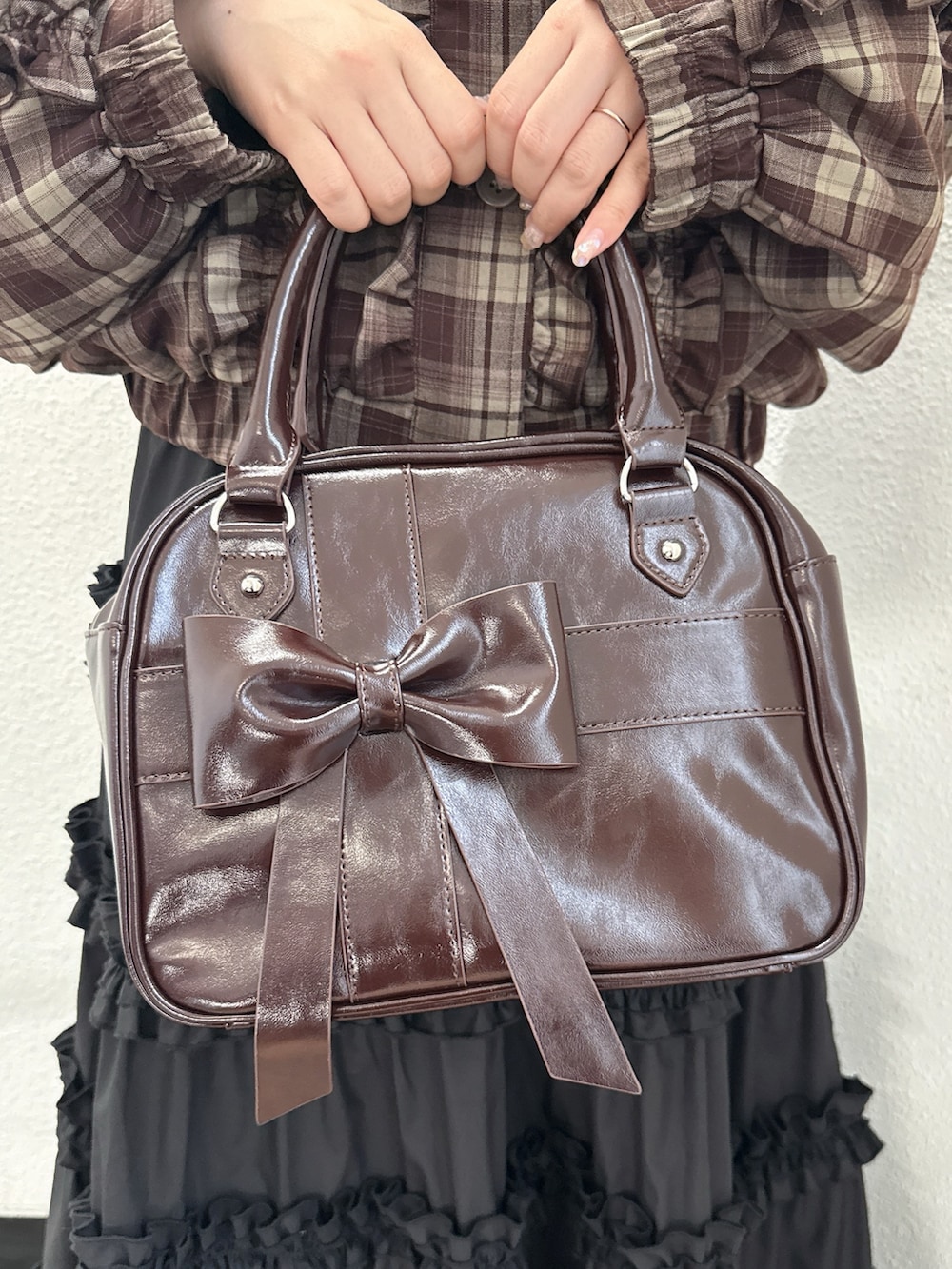 ブラウン系のブルゾン、ブラック系のスカート、ブラウン系のハンドバッグを着用したレディースの夏コーディネートの7枚目の写真
