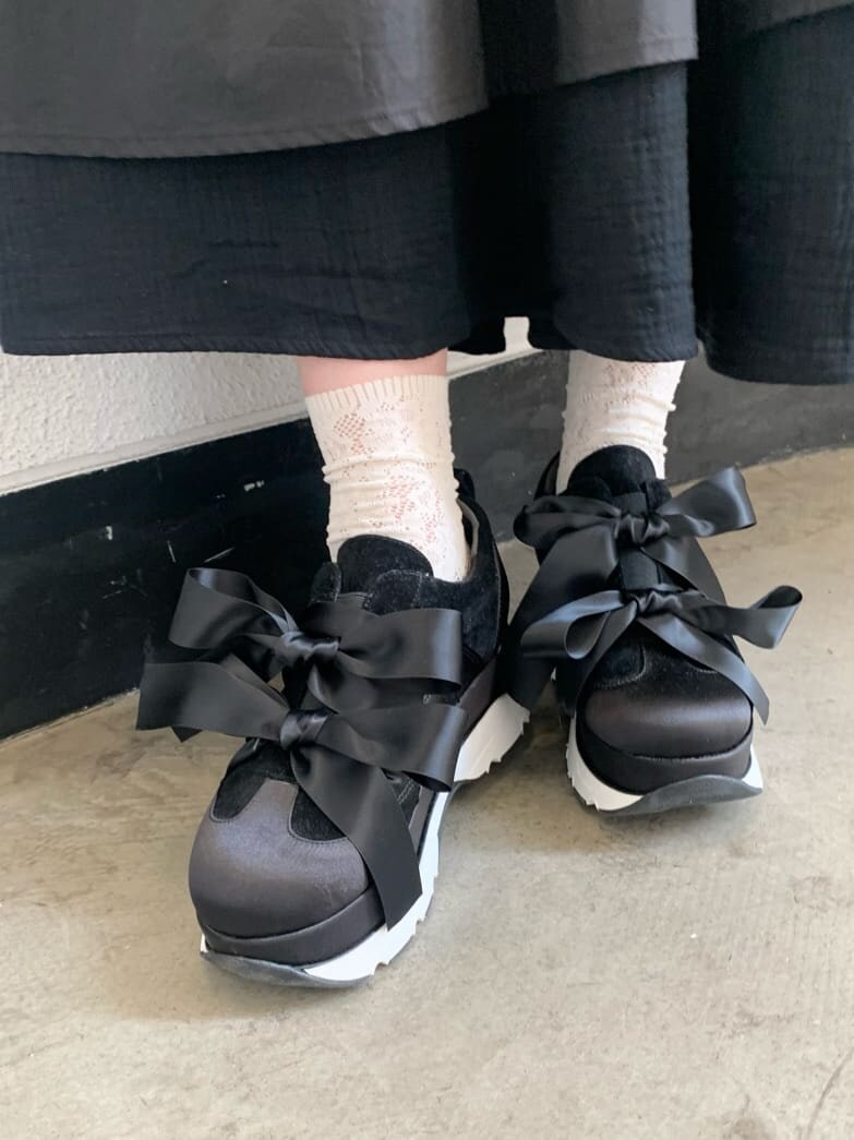 ブラック系のスカート、ブラック系のスニーカー、ホワイト系のTシャツ/カットソーを着用したレディースの夏コーディネートの3枚目の写真