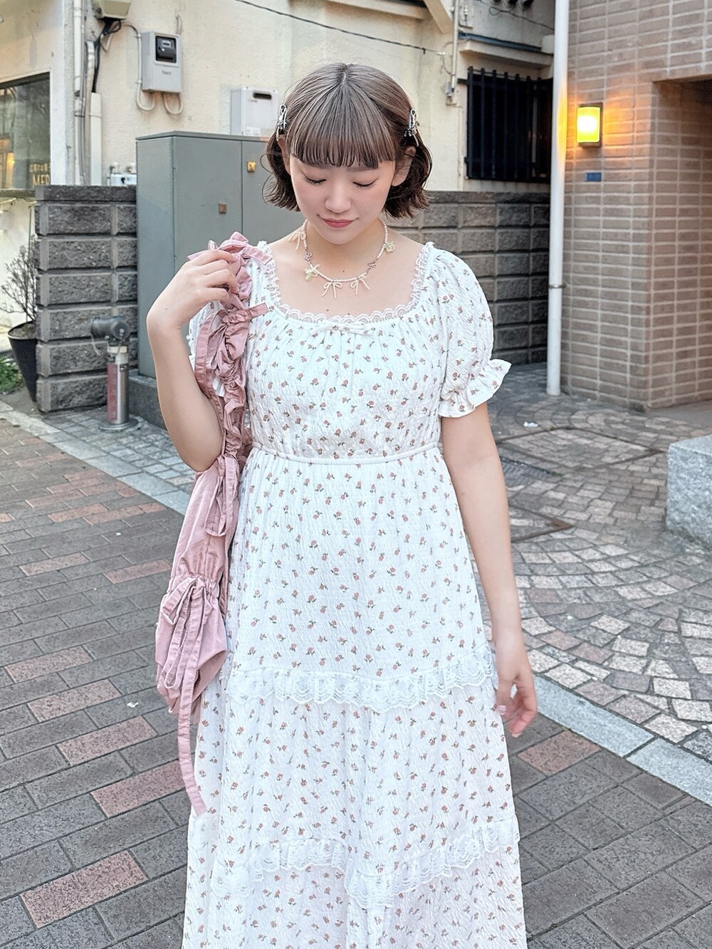 ピンク系のトートバッグ、ベージュ系のサンダル、ホワイト系のワンピースを着用したレディースの春コーディネートの6枚目の写真