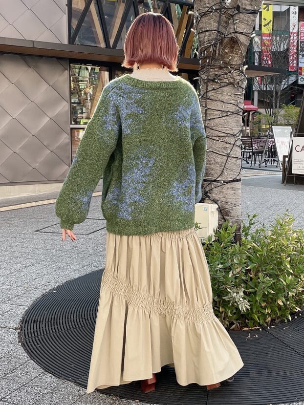 グリーン系のカーディガン/ボレロ、ベージュ系のスカート、ホワイト系のニット/セーターを着用したレディースの冬コーディネートの3枚目の写真