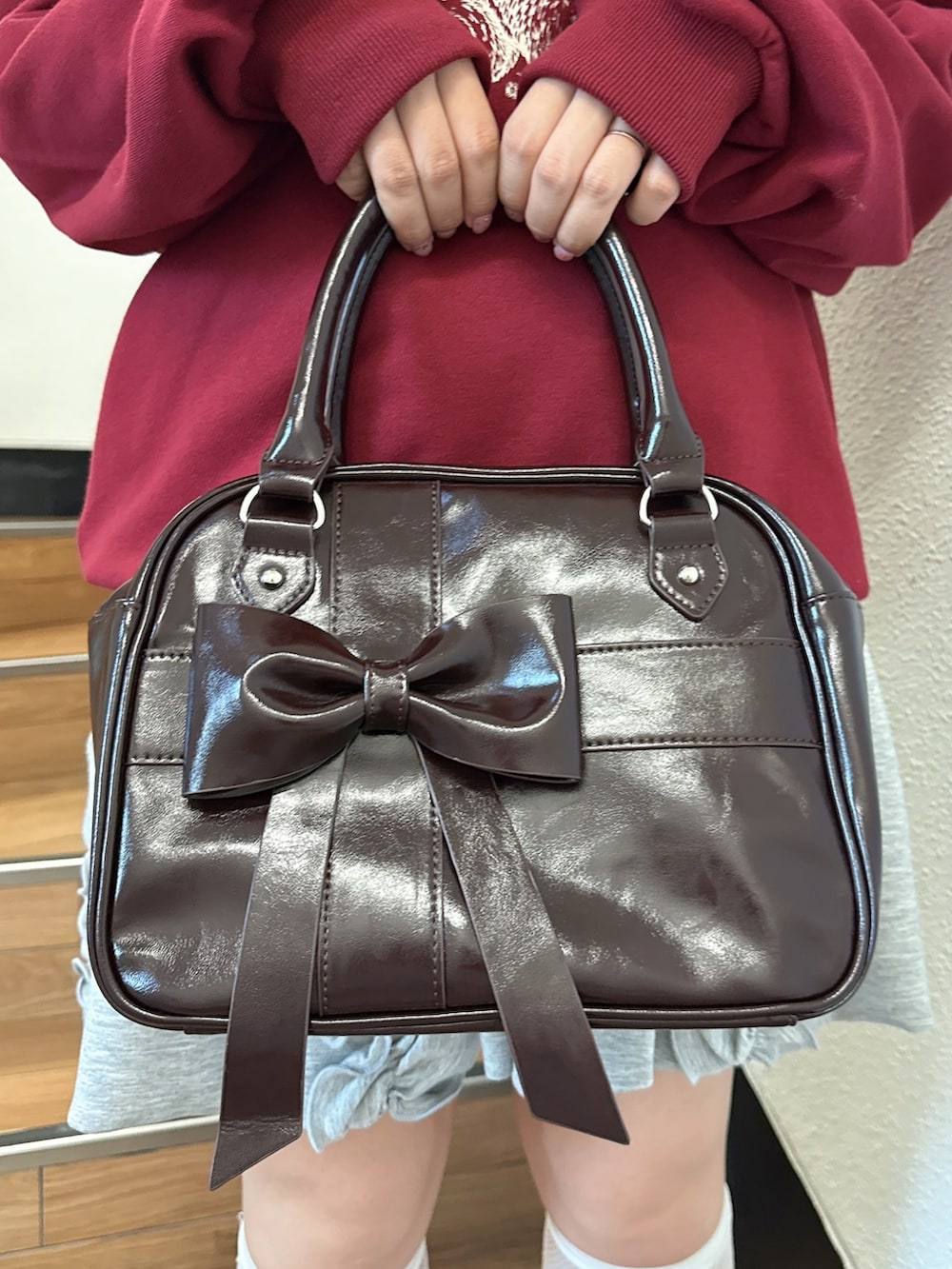 レッド系のスウェット、グレー系のスカート、ブラウン系のハンドバッグを着用したレディースの夏コーディネートの7枚目の写真