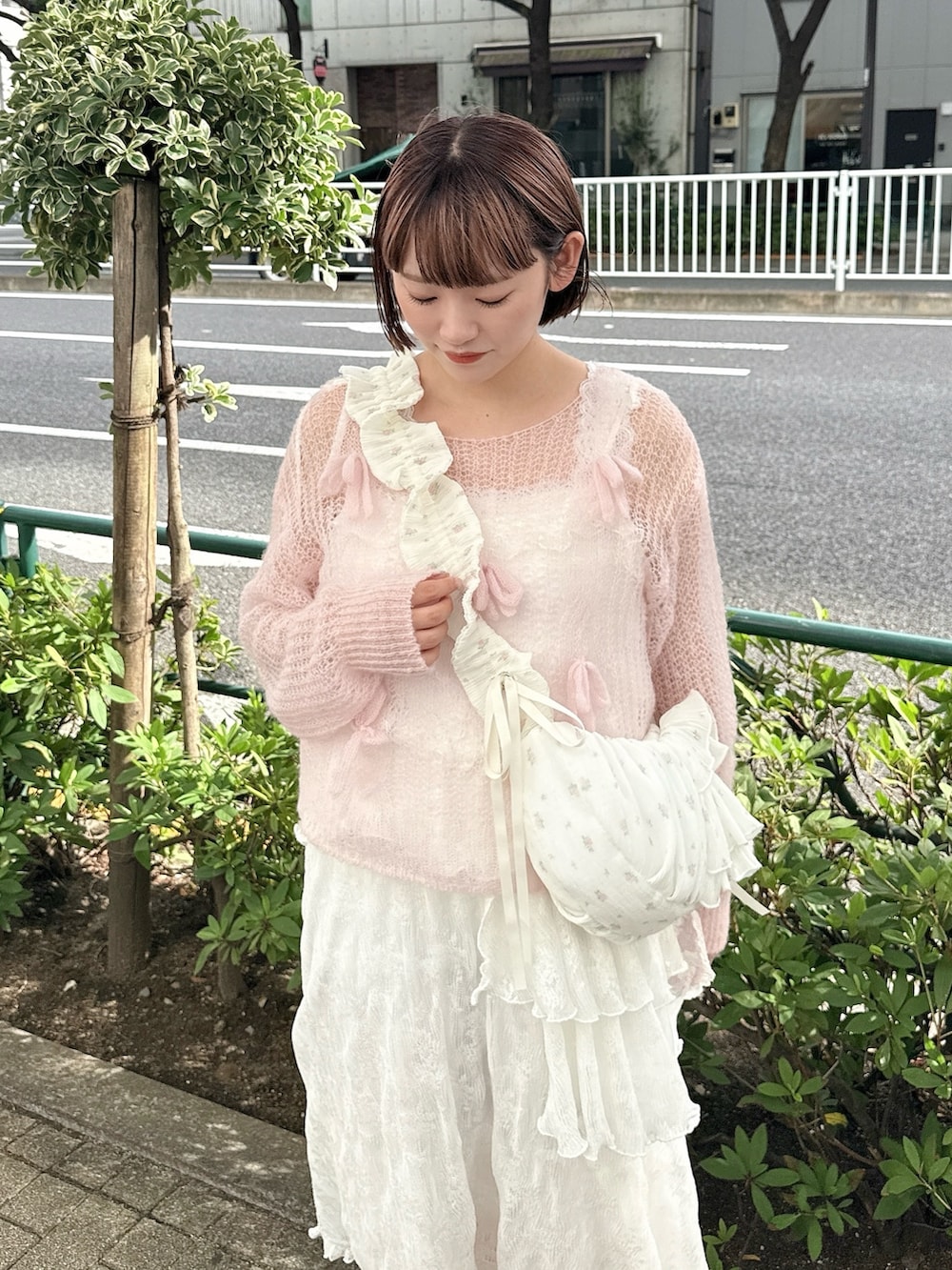 ピンク系のニット/セーター、ホワイト系のショルダーバッグ、ホワイト系のワンピースを着用したレディースの夏コーディネートの3枚目の写真