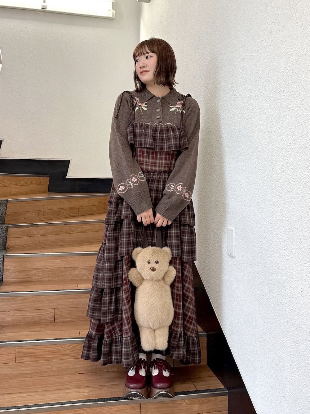 ブラウン系のニット/セーター、レッド系のワンピース、ベージュ系のハンドバッグを着用したレディースの秋コーディネートの2枚目の写真