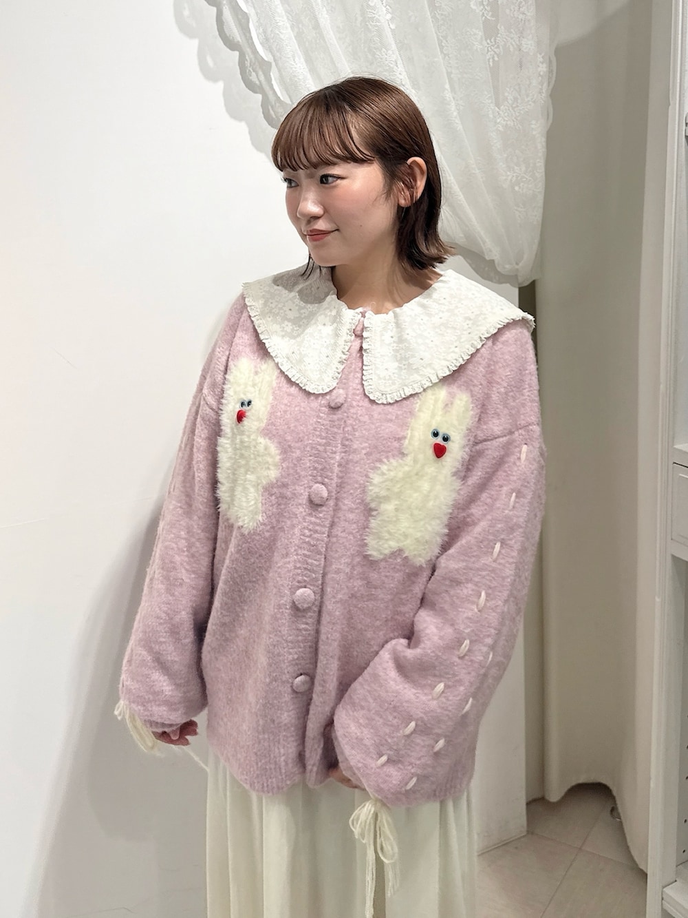 ピンク系のブーツ、ピンク系のカーディガン/ボレロ、ホワイト系のワンピースを着用したレディースの秋コーディネートの5枚目の写真