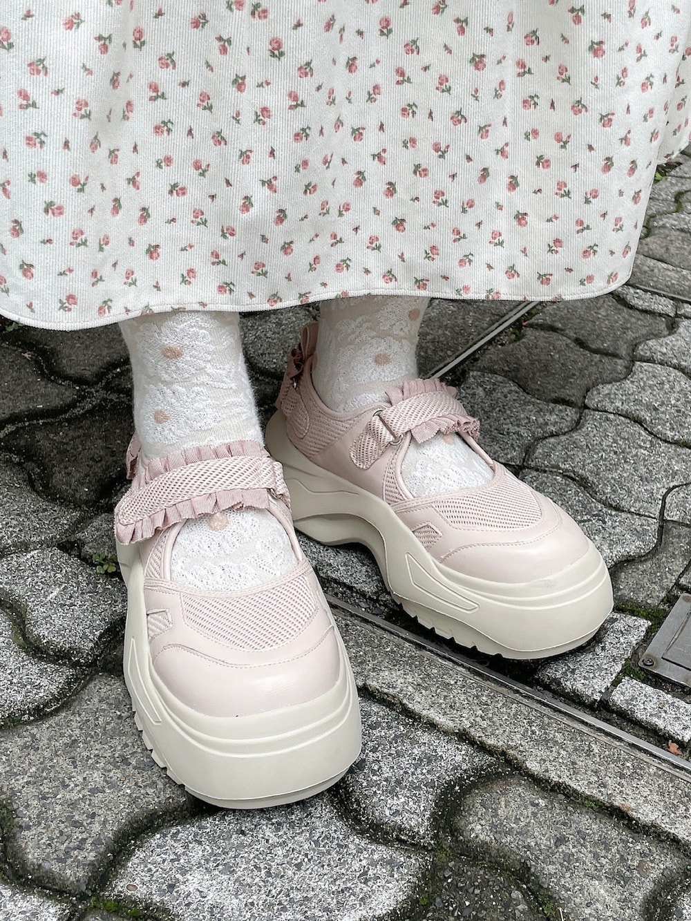 ホワイト系のジャンパースカート、ピンク系のカーディガン/ボレロ、グレー系のニット/セーターを着用したレディースの秋コーディネートの6枚目の写真